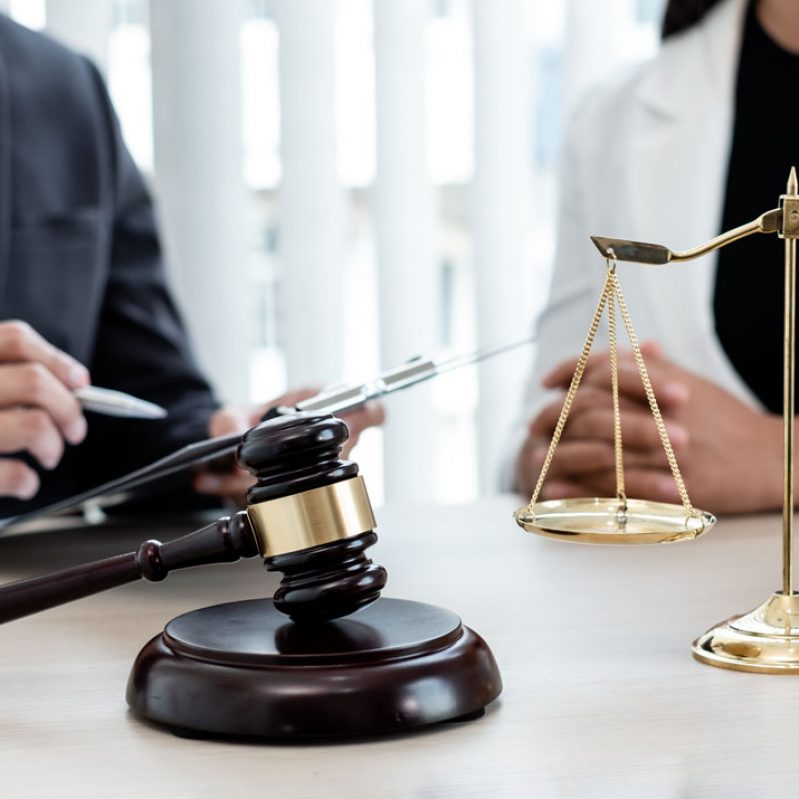 A male lawyer or a judge counseling clients about judicial justice and prosecution with scales, judges gavel, legal documents legal services concept.; Shutterstock ID 1818601994; purchase_order: -; job: -; client: -; other: -
